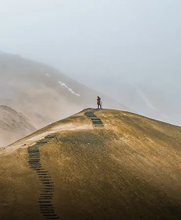 A walker on a grassy ridge above the valley