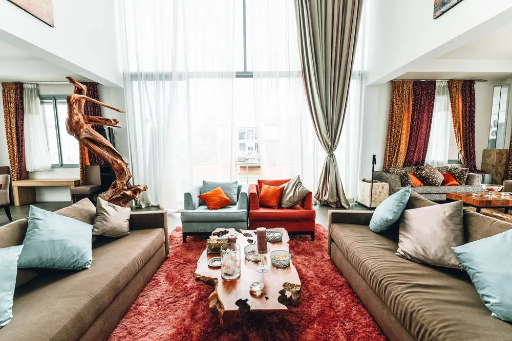 The guest lounge with two sofas, a red rug and tall windows